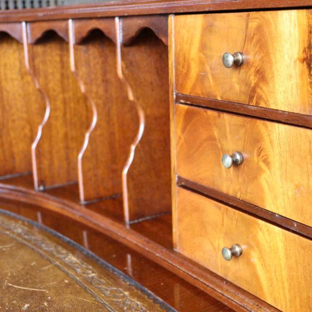 Vintage teak mid-century British desk with smooth wood grain, rounded edges, and three metal-knob drawers, showcasing.