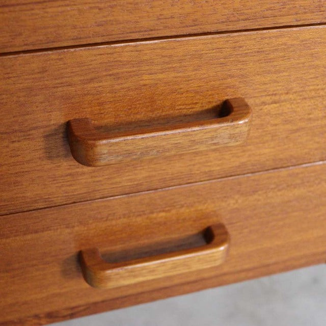 Close-up of vintage mid-century teak desk drawer with smooth wood grain and recessed rectangular handles from Denmark.
