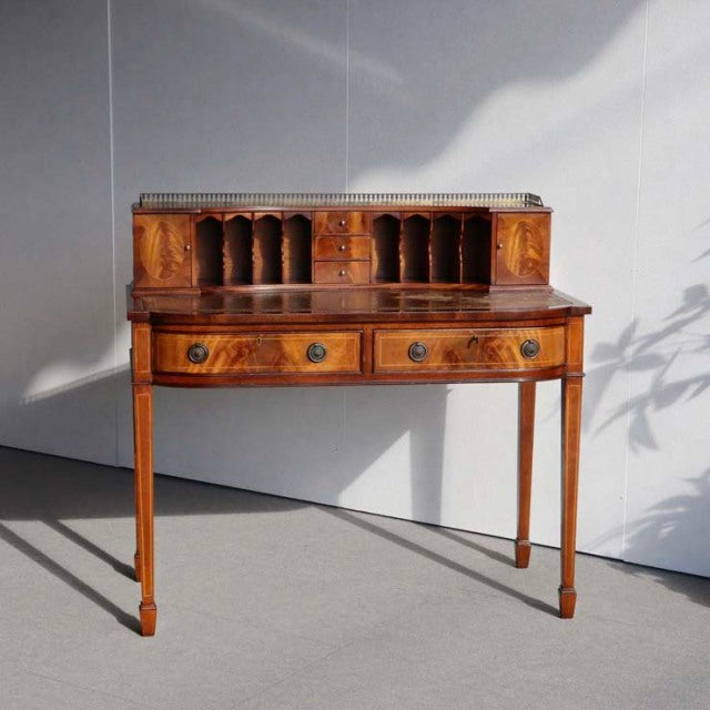 Mid-century vintage British teak desk with curved front, tapered legs, multiple small compartments, and rich wood grain.