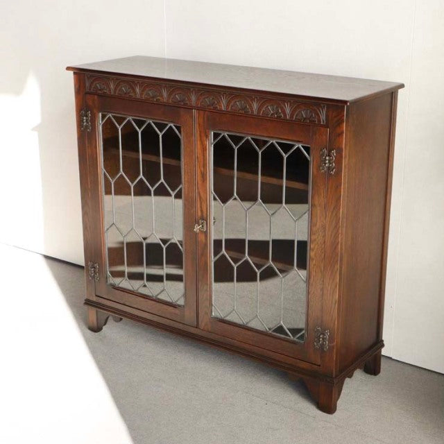 Vintage teak British mid-century Jaycee cabinet with decorative wood grain, glass-paneled doors, and sturdy carved legs.
