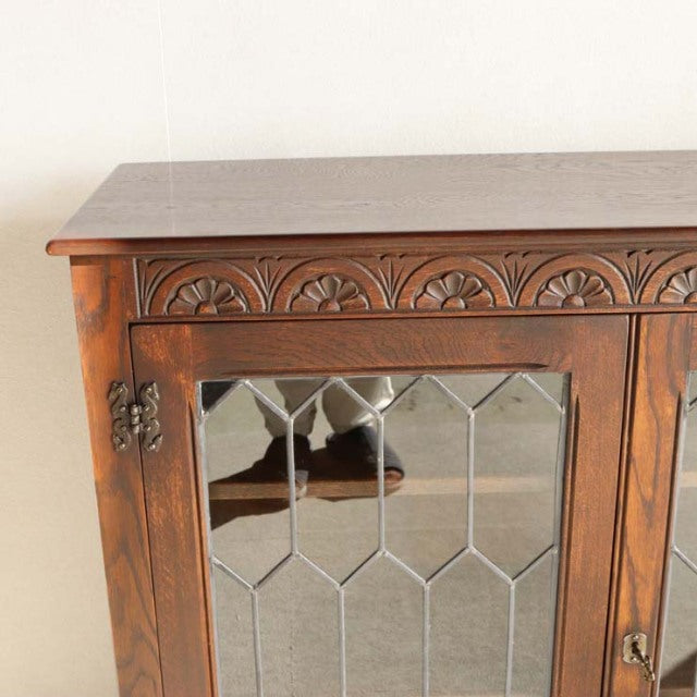 Vintage British teak cabinet by Jaycee with carved floral detailing and leaded glass doors, mid-century design.