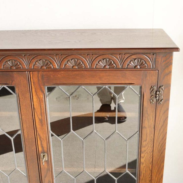 Vintage mid-century teak cabinet by British Jaycee, detailed wood grain, ornate carved top edge, glass paneled doors with.