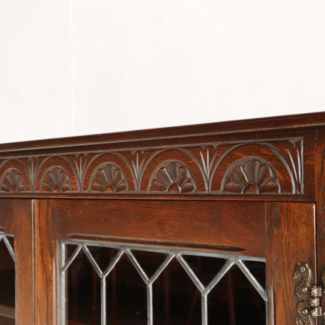 British mid-century vintage teak cabinet with intricate carved floral border and diamond-patterned glass panels.
