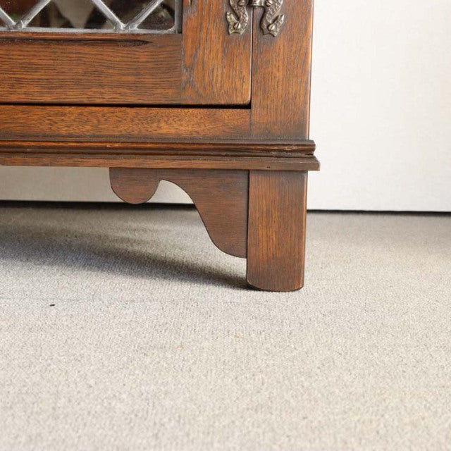 Mid-century British teak cabinet leg with carved bracket detail and rich wood grain texture.