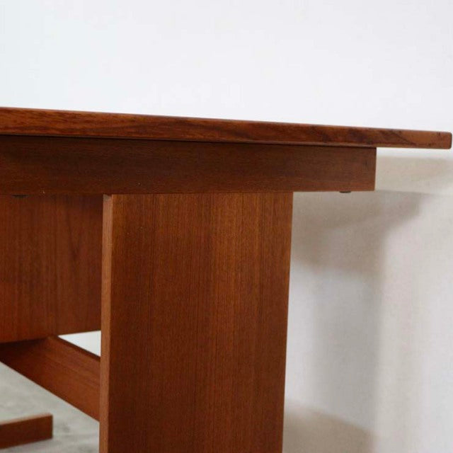 Mid-century Danish teak desk with rich wood grain, clean lines, and sturdy rectangular legs.