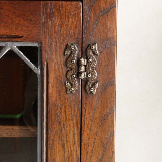 Close-up of vintage British teak cabinet door with intricate mid-century brass seahorse hinges and rich wood grain from.