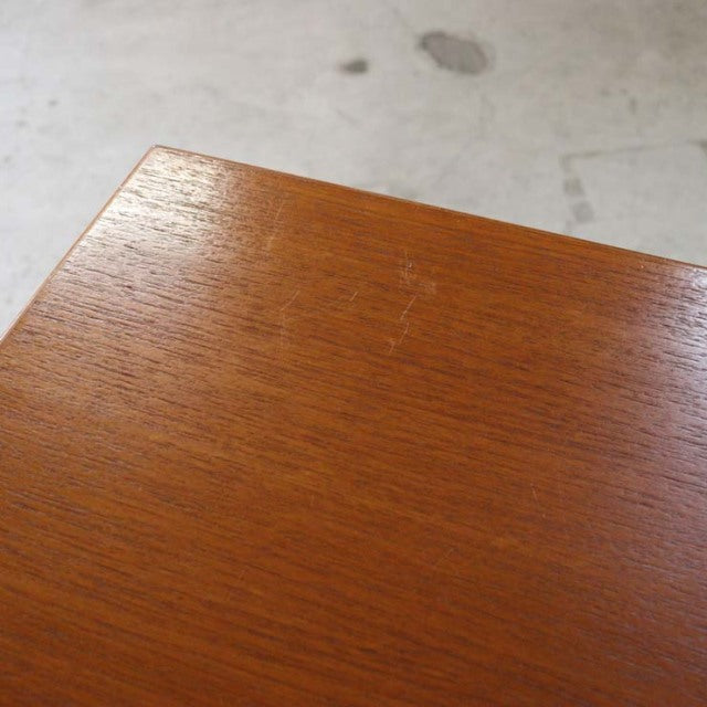 Close-up of vintage teak desk surface showing warm wood grain and smooth mid-century Danish craftsmanship.