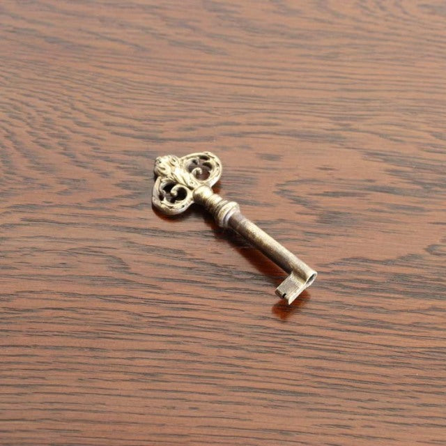 Antique brass skeleton key on vintage teak wood surface with visible grain.