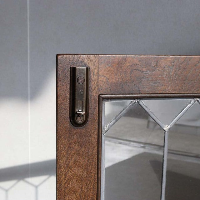 Close-up of vintage Jaycee British teak cabinet door corner with textured wood grain and metal latch, mid-century design.
