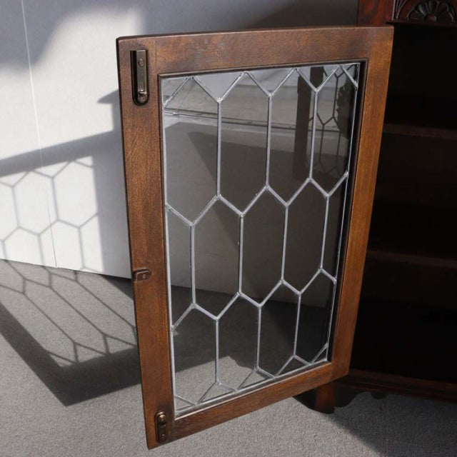 Vintage teak cabinet door with British mid-century leaded glass panels and visible wood grain.