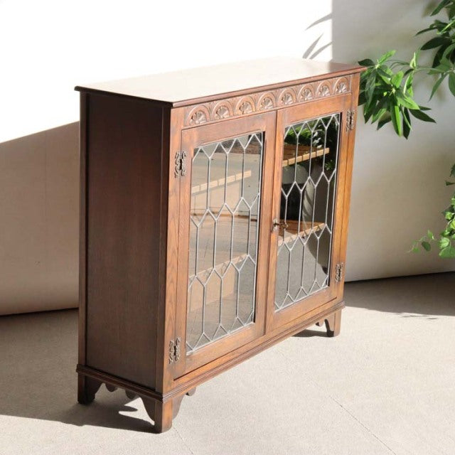 Vintage teak mid-century British Jaycee cabinet with decorative glass paneled doors and tapered legs.
