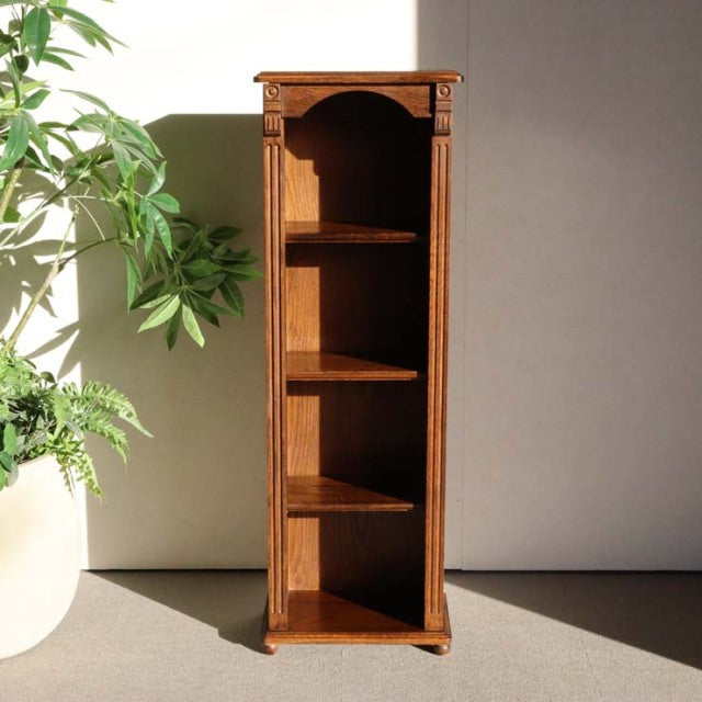 Tall vintage teak cabinet with British mid-century design, showcasing rich wood grain, carved top edge, and slender legs.