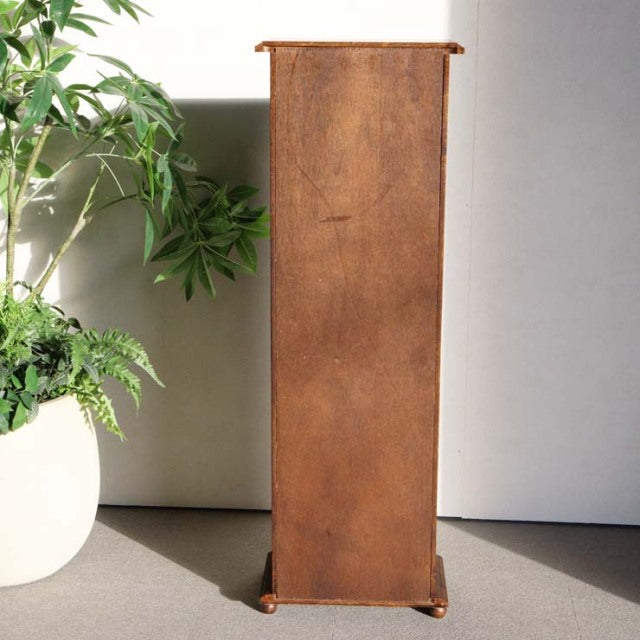 Tall vintage teak cabinet with rich wood grain, slender rectangular profile, standing on small rounded feet, mid-century.