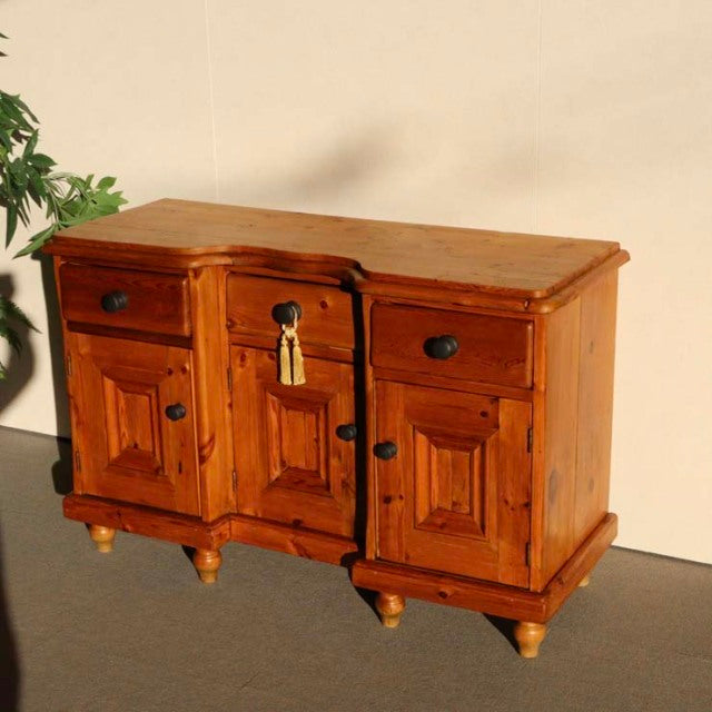 Vintage teak British mid-century sideboard with rich wood grain, three drawers, paneled doors, and turned legs.