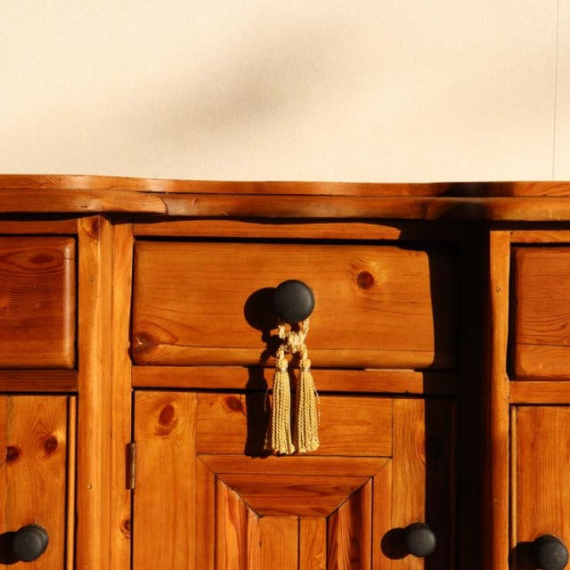 Vintage teak mid-century British sideboard with rich wood grain, black round knobs, and tasseled drawer pull, crafted in.