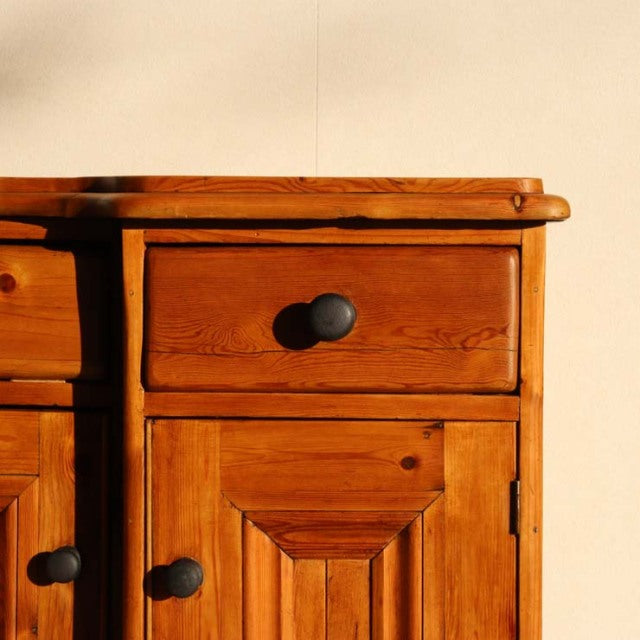 Vintage teak sideboard with rich wood grain, mid-century British design, rounded edges, and black round knobs.