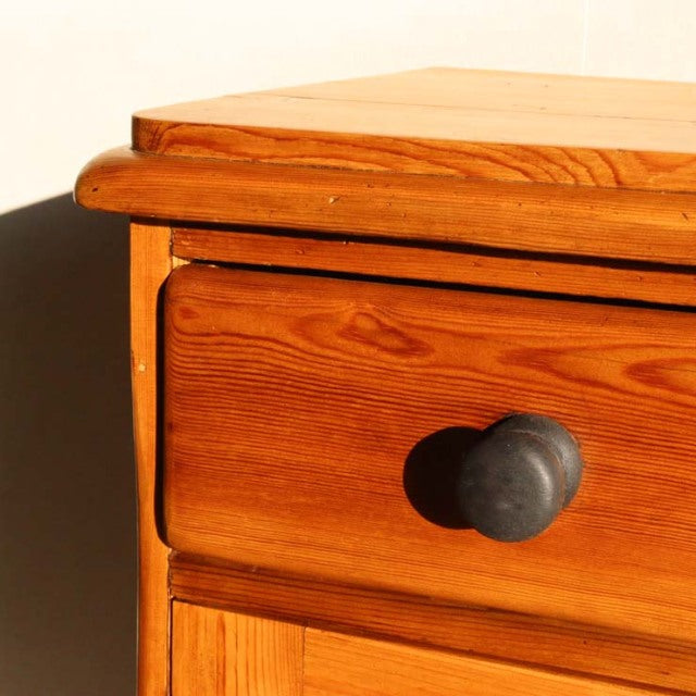 Vintage teak sideboard drawer front showcasing rich wood grain and rounded black knob in mid-century British design style.