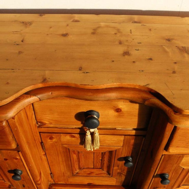 Vintage teak mid-century sideboard with rich wood grain, ornate curved top edge, black round knobs, and classic.