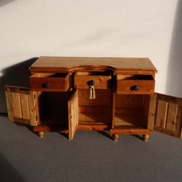 Vintage teak sideboard with rich wood grain, three drawers, and three cabinet doors on tapered mid-century British legs.