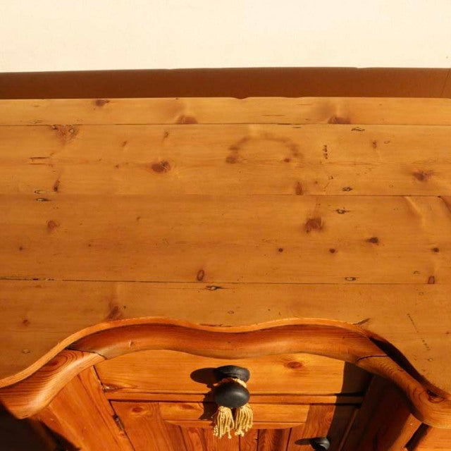 Vintage teak British mid-century sideboard with warm wood grain, curved top edge, and black round knob handle.
