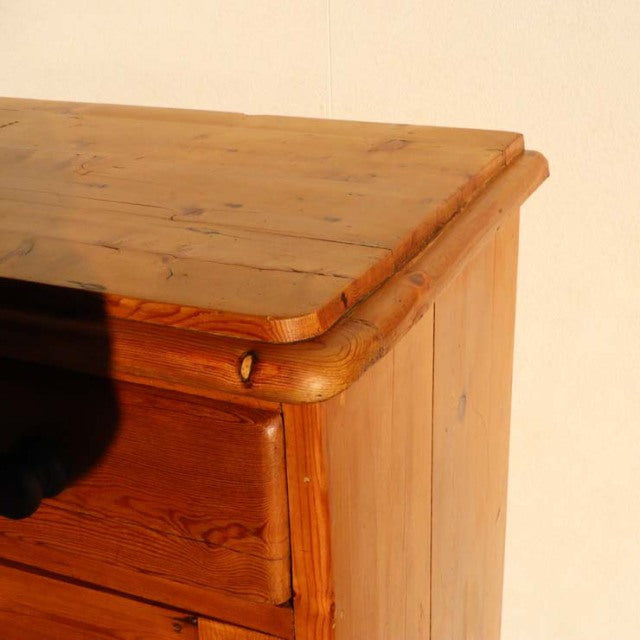 Vintage teak mid-century sideboard corner with smooth rounded edges, visible wood grain, and warm honey finish.