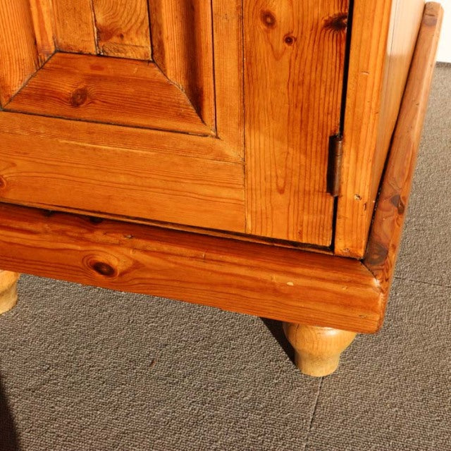 Corner detail of vintage teak sideboard showing rich wood grain, knotted texture, and turned mid-century legs in warm.