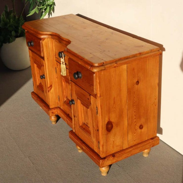 Vintage teak sideboard with rich wood grain, British mid-century design, curved top edges, black metal handles, and turned.