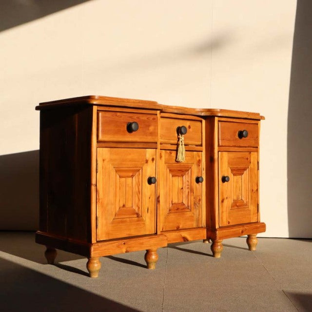 Vintage teak sideboard in British mid-century style with intricate wood grain, three drawers, and rounded legs.