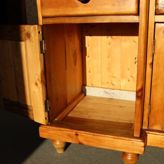 Vintage teak British mid-century sideboard cabinet open door showing rich wood grain and rounded wooden legs.