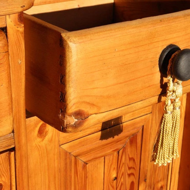 Close-up of vintage teak sideboard drawer with visible wood grain, dovetail joints, and black knob with tassel, showcasing.