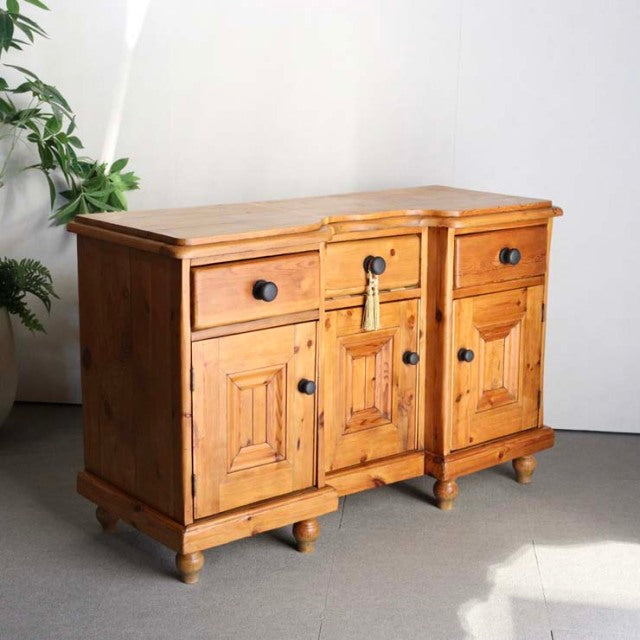 Vintage teak sideboard with rich wood grain, British mid-century style, featuring three drawers and paneled doors on rounded .