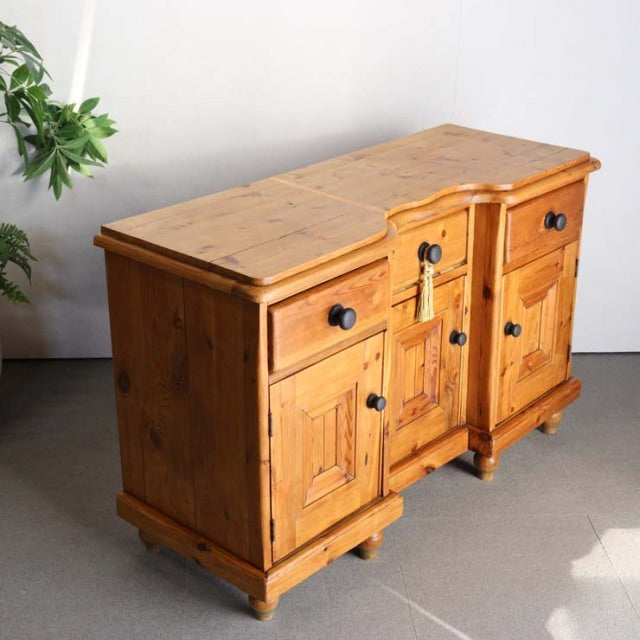 Vintage mid-century British sideboard made from warm teak with prominent wood grain, featuring panelled doors, black metal.