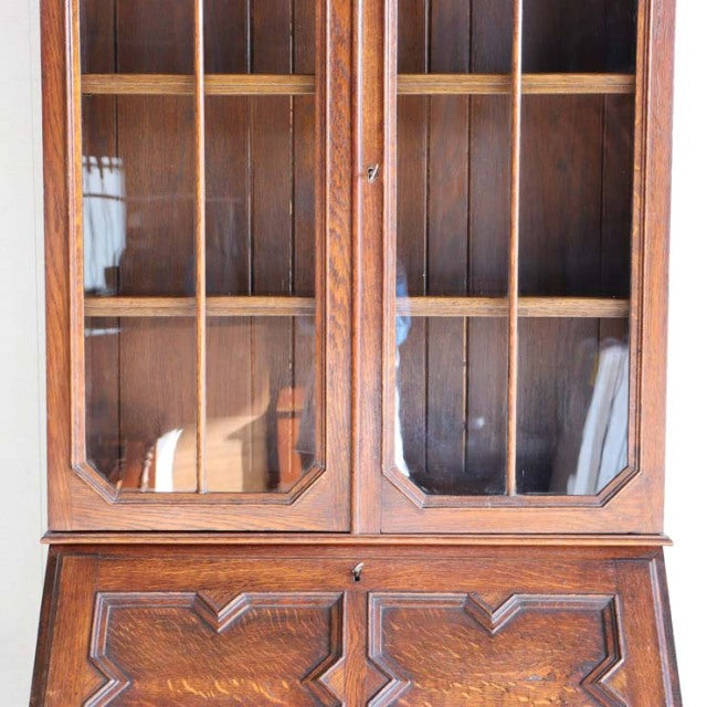 Mid-century British vintage teak cabinet with glass paneled doors, geometric wood grain details, and sturdy legs.
