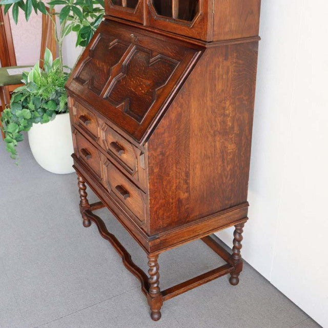 Vintage 1930s British teak cabinet with ornate grain, drop-front desk, turned legs, and carved detailing.