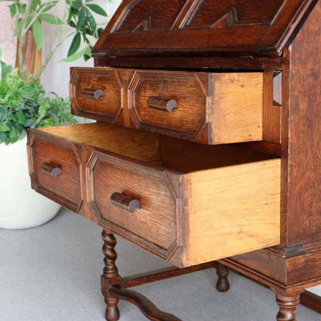 Vintage British teak cabinet from the 1930s with rich wood grain, carved drawer fronts, and turned legs, showcasing.
