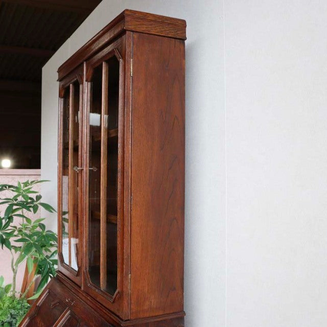 Vintage 1930s British teak cabinet with mid-century design, detailed wood grain, tall glass doors, and solid rectangular.