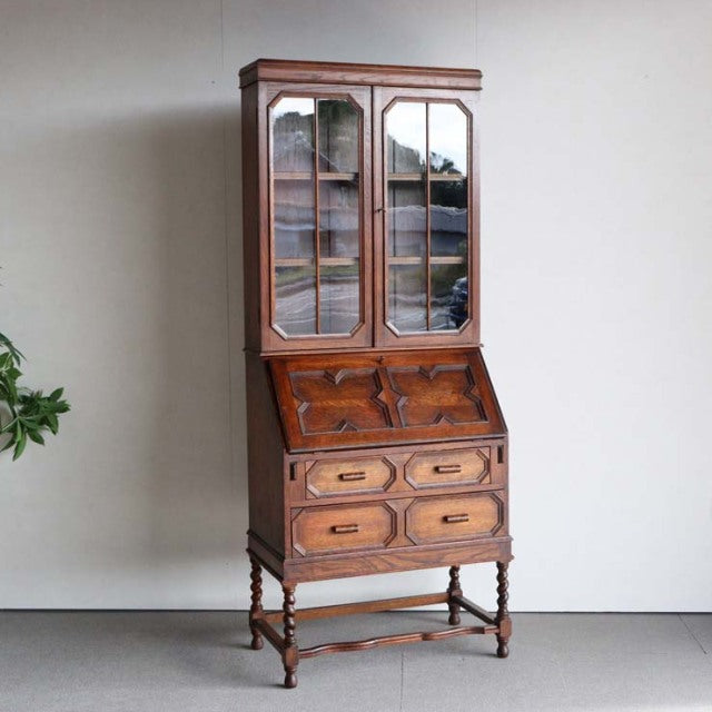 Vintage mid-century British teak cabinet from the 1930s with glass-paneled upper doors, detailed wood grain, drop-front.