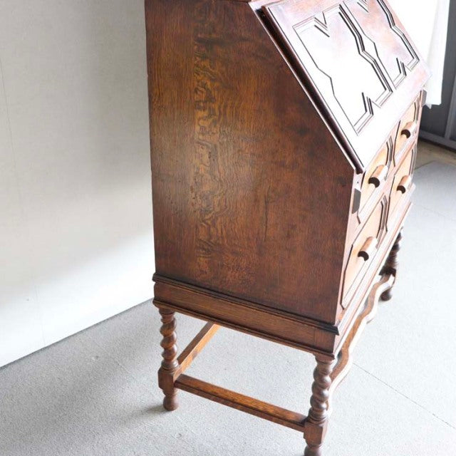 Mid-century British vintage teak cabinet with rich wood grain, ornate turned legs, and detailed drawer fronts.