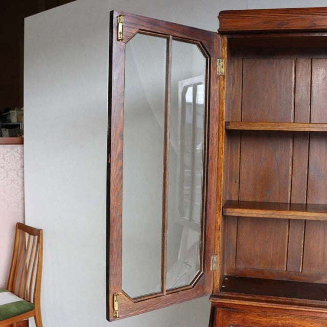 Mid-century British vintage teak cabinet with beveled glass door, brass hinges, and visible wood grain on open shelving unit.
