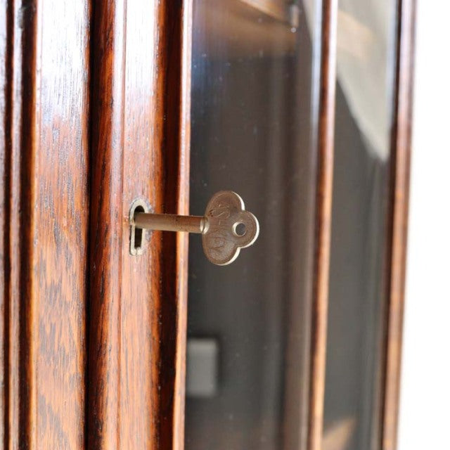 Vintage teak British mid-century cabinet with rich wood grain and antique metal key in glass door lock.