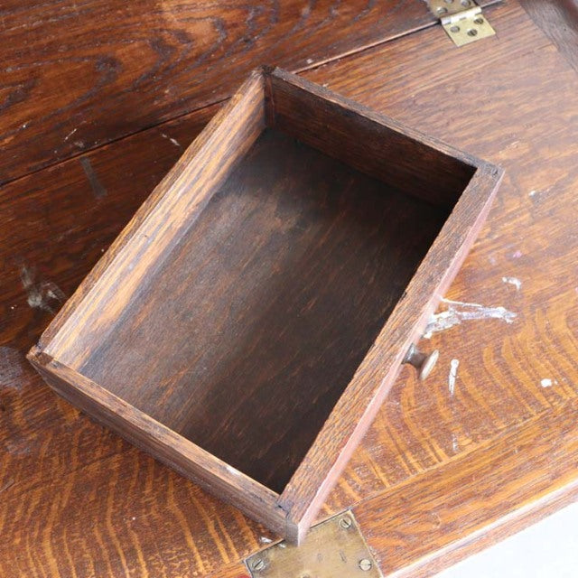 Vintage teak drawer open on mid-century British oak cabinet, showing rich wood grain and brass hinge detail.
