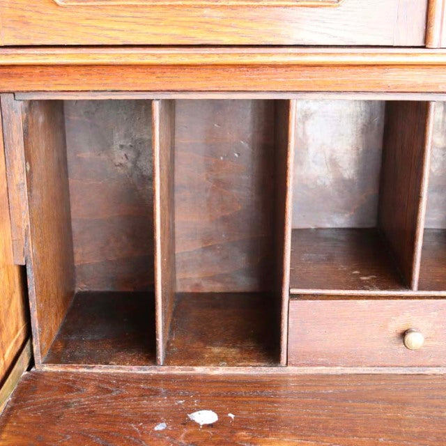 Close-up of vintage British teak cabinet interior with vertical dividers, small drawer with round wooden knob, and visible.