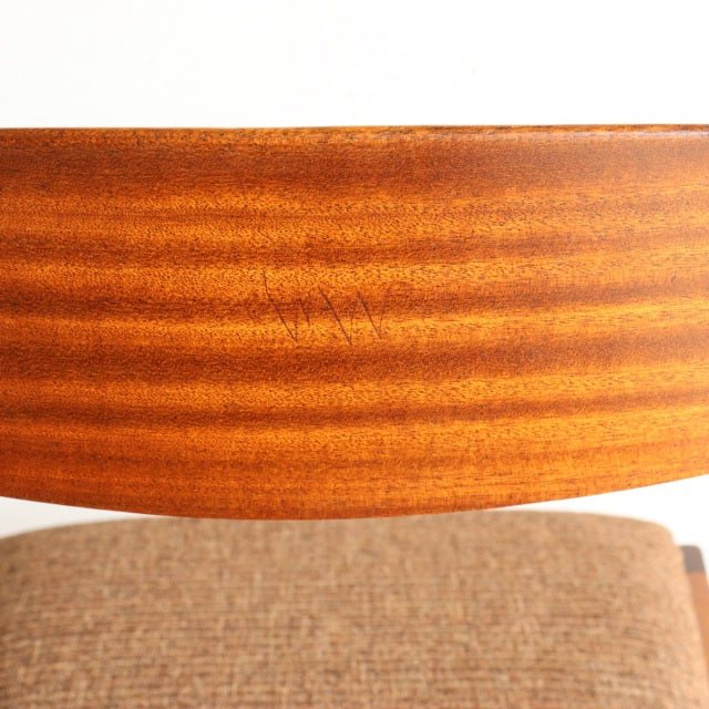 Mid-century McIntosh dining chair backrest in warm teak wood with visible grain above textured beige fabric seat cushion.