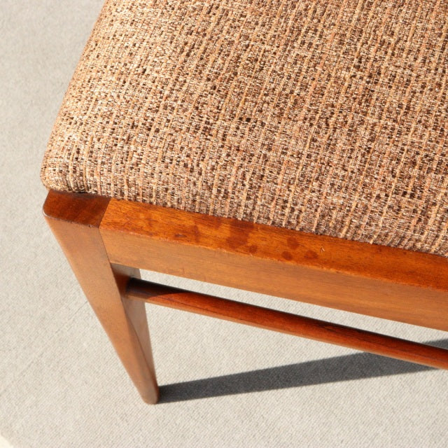 Close-up of vintage British mid-century teak dining chair by McIntosh, showing textured beige fabric seat and smooth wood.