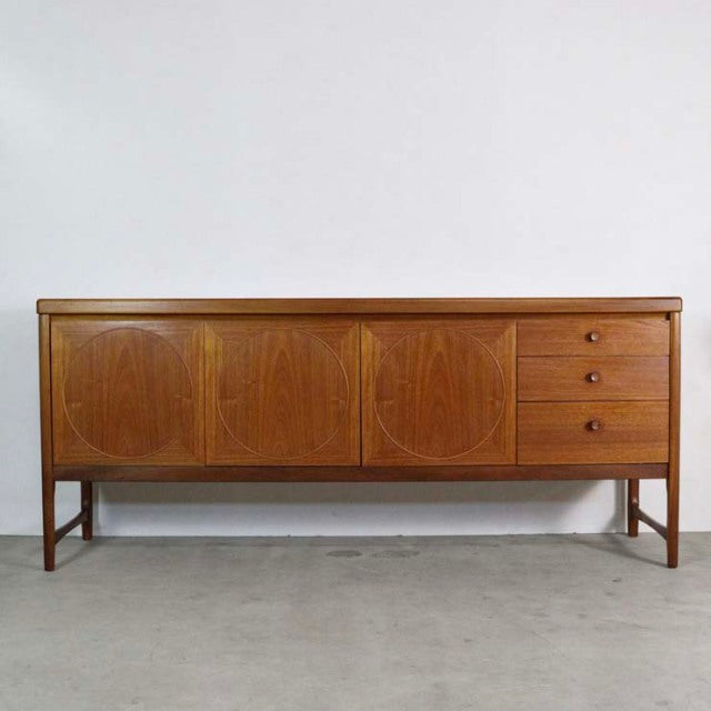 Mid-century British vintage teak sideboard by Nathan, featuring circular wood grain patterns, three drawers on the right,.