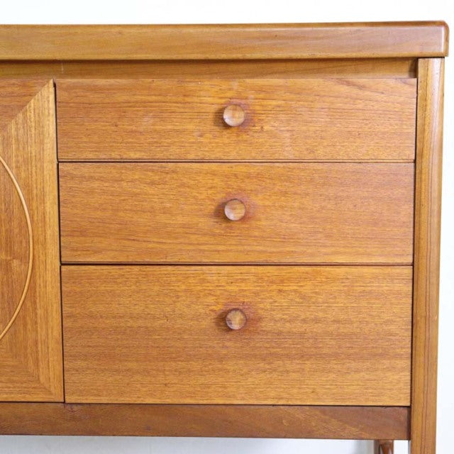 Vintage teak mid-century sideboard by British brand Nathan with rich wood grain and three round wooden drawer knobs.