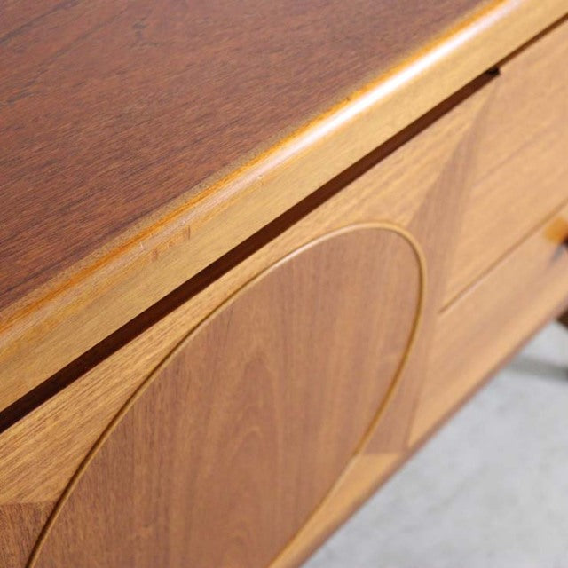 Mid-century British vintage teak sideboard by Nathan with smooth grain and circular recessed detail on drawer front.