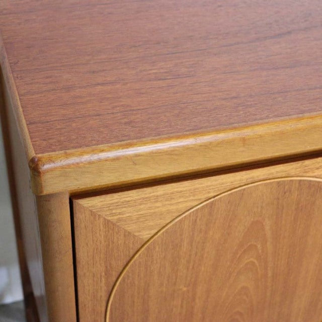 Vintage teak British sideboard corner showing smooth wood grain and rounded door edge, mid-century Denmark design.