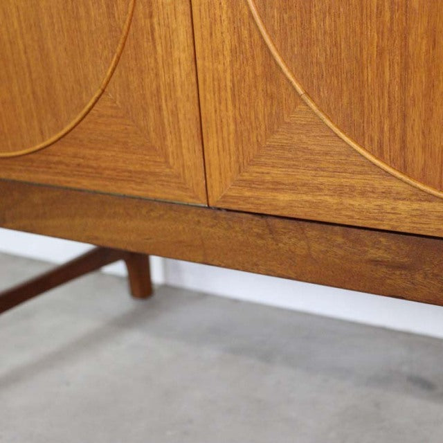 Mid-century British Nathan teak sideboard with rich wood grain, circular door insets, and tapered legs in excellent vintage.