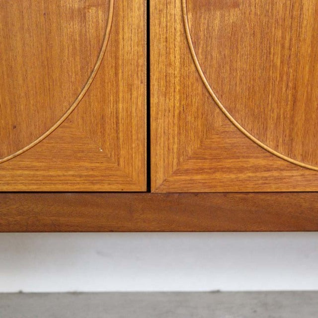 Close-up of vintage British mid-century Nathan teak sideboard doors featuring curved inlaid wood grain and smooth finish.